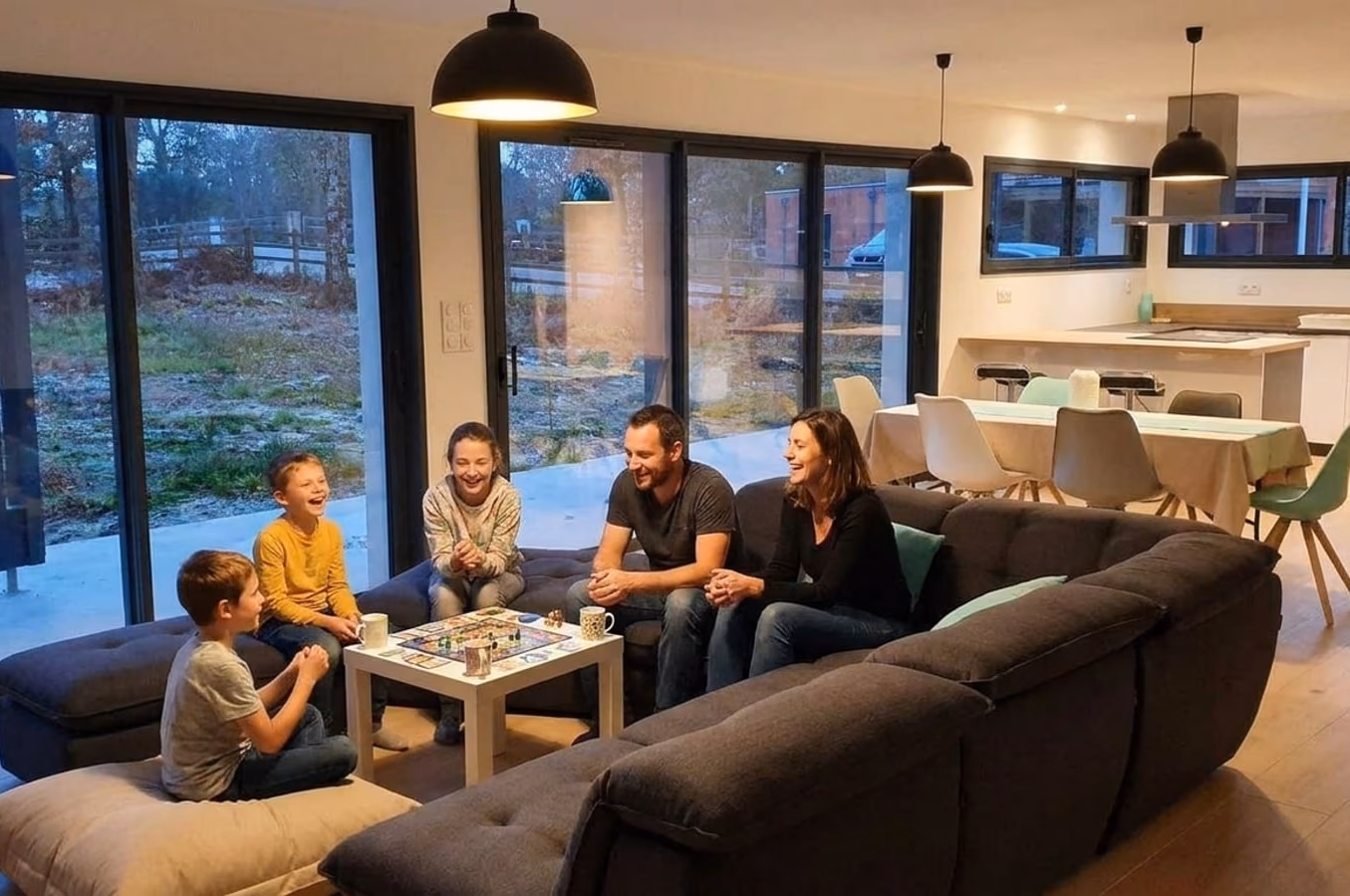 Famille qui joue à un jeu de société dans le salon le soir, maison Landes Habitat à Moliets-et-Maâ (40)