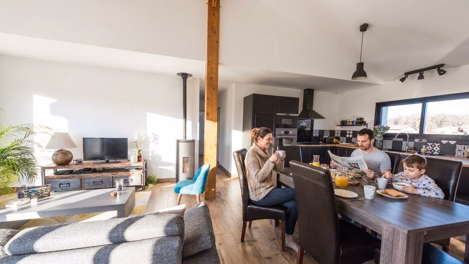 Famille au petit-déjeuner dans la pièce de vie ensoleillée d'une maison Landes Habitat à Saint-Julien-en-Born (40)
