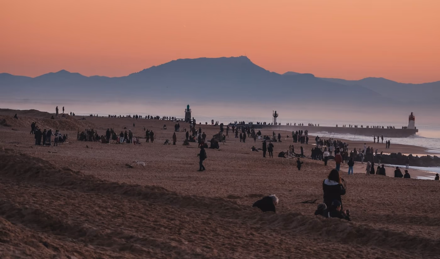 Promeneurs sur la plage d'Hossegor (40) au coucher du soleil, la Rhune et les phares de Capbreton au loin