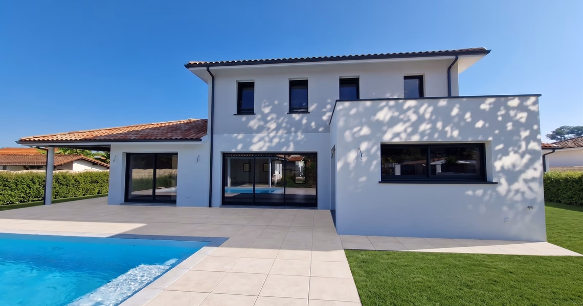 Façade arrière d'une maison contemporaine à étage avec piscine, larges baies vitrées coulissantes et extension à toit plat.