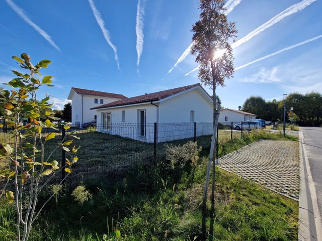 Vue ensoleillée sur le jardin et la façade latérale d'une maison livrée par Landes Habitat, secteur Maremne.