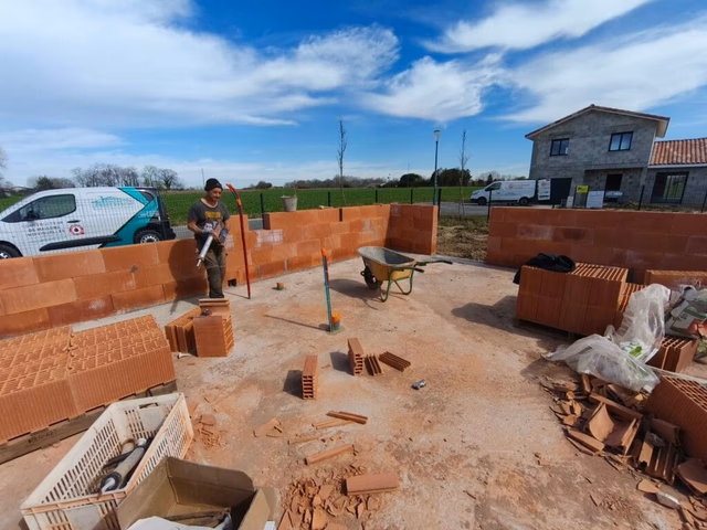 Artisan maçon posant des briques rectifiées Bio'bric sur un chantier de maison à Saubrigues