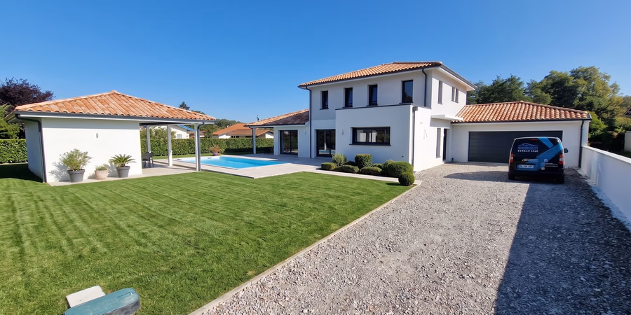 Maison individuelle contemporaine à étage avec enduit blanc, toiture en tuiles et piscine extérieure.
