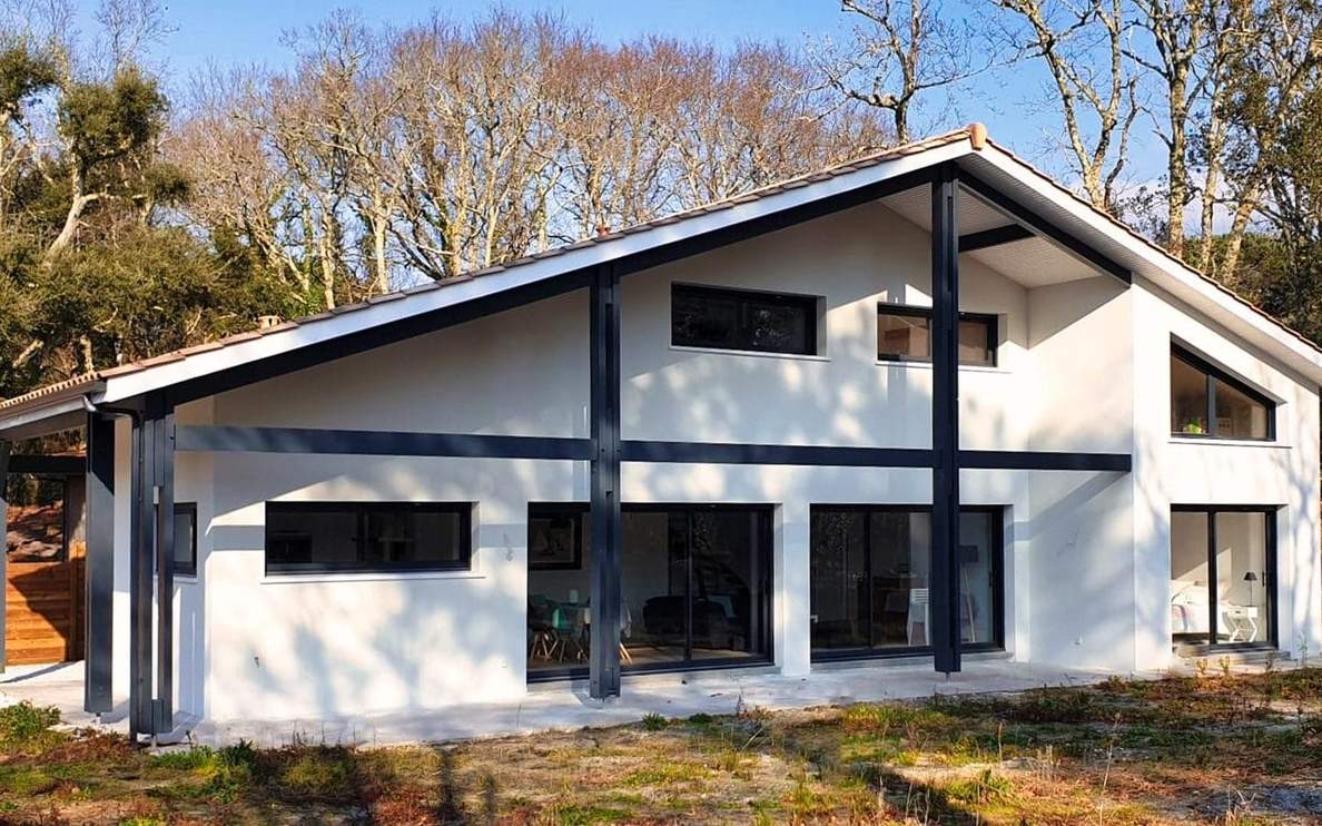 Façade moderne d'une maison familiale à Moliets avec bardage foncé et larges baies vitrées