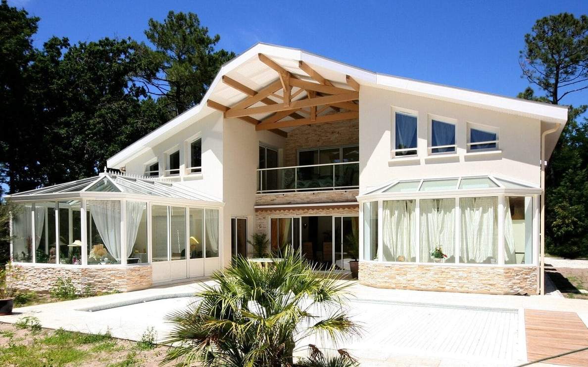Maison R+1 contemporaine de 345 m² à Vieux-Boucau-les-Bains avec charpente apparente, double véranda et parement pierre - Construction Landes Habitat