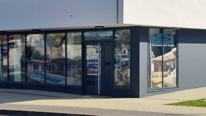 Vitrine de l'agence Landes Habitat avec des visuels de maisons et de piscines sur les vitres.