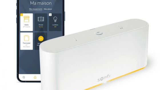 Un boîtier blanc Somfy et un smartphone affichant une application de contrôle domotique.