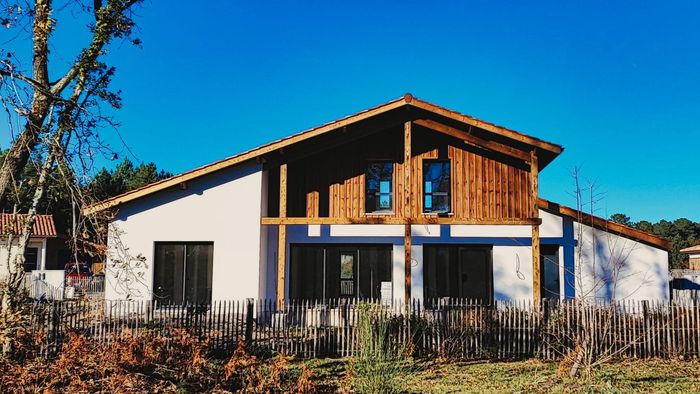 Façade de la maison landaise contemporaine construite à Moliets-et-Maa, alliant bardage bois et crépi blanc.