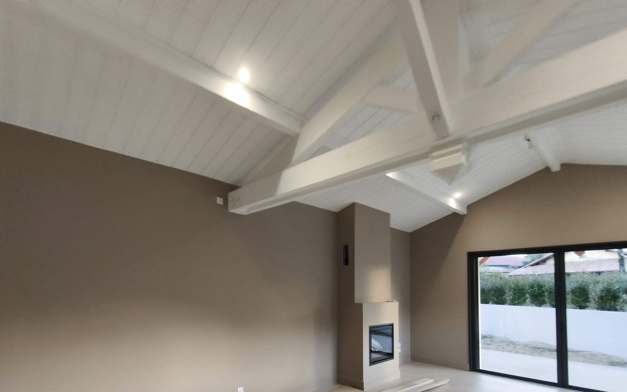 Charpente apparente peinte et poêle contemporain dans une maison rénovée à Capbreton