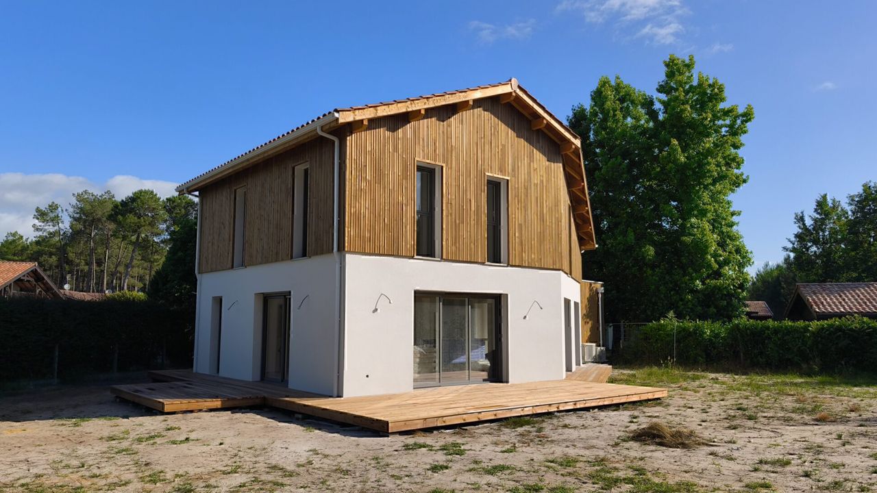 Maison contemporaine à deux niveaux avec bardage bois à l'étage et terrasse en bois